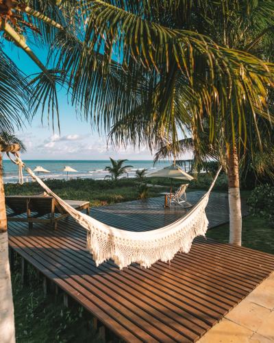 a hammock on a beach with a view of the ocean at Pousada Vila Sagui in Maragogi