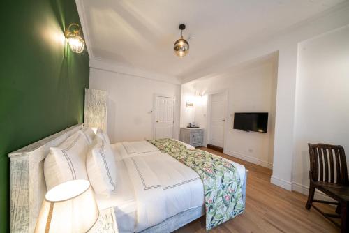 a bedroom with a white bed and a green wall at Pedro Barn Hotel at Little England Cottages in Nuwara Eliya