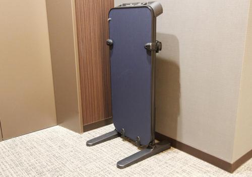 a blue suitcase is standing in a bathroom stall at Hotel Trend Fukuyama Ekimae in Fukuyama