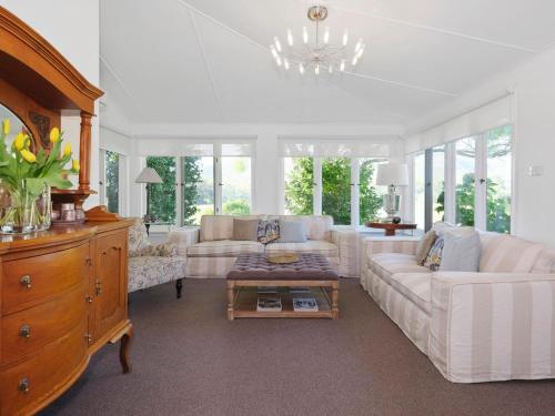una sala de estar con muebles blancos y una lámpara de araña. en Meerea Country Estate adjoining Wollombi National Park en Bulga