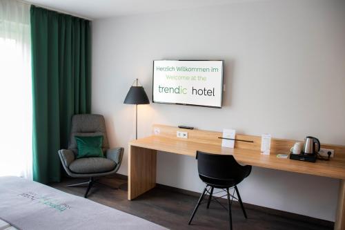 a room with a desk, chair and a television at trendic hotel in Marktoberdorf