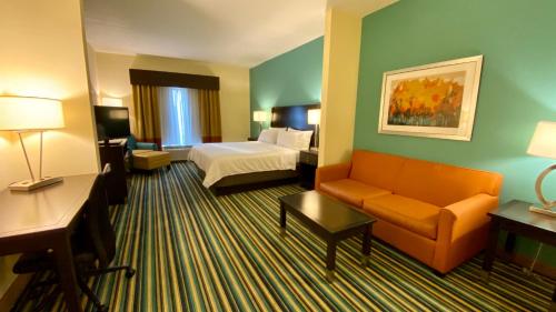 a hotel room with a bed and a couch at Holiday Inn Express Hotel & Suites Orlando East-UCF Area by IHG in Orlando