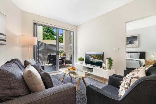 a living room with a couch and a tv at CENTRAL NO 5 LUXURY APARTMENT in Kiama