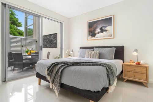 a bedroom with a large bed and a balcony at CENTRAL NO 5 LUXURY APARTMENT in Kiama
