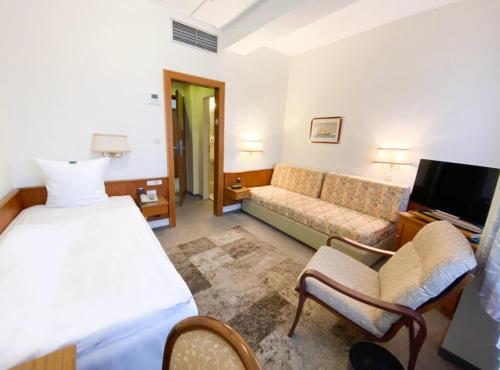 ein Hotelzimmer mit einem Bett und einem Sofa in der Unterkunft Hotel am Rathaus in Flensburg