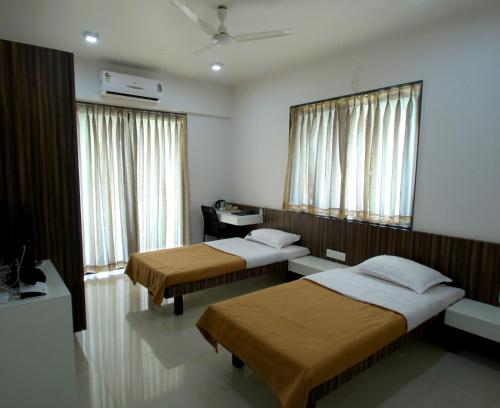 a hotel room with two beds and a mirror at Aashiyana Inn in Nashik