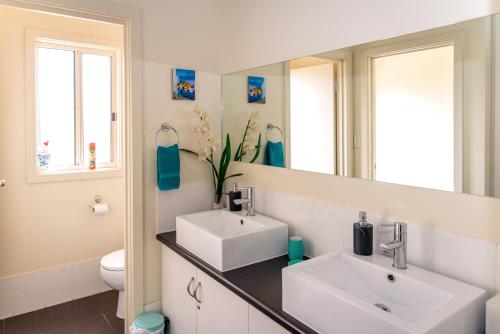 Baño con 2 lavabos y espejo en McLaren Vale Studio Apartments en McLaren Vale