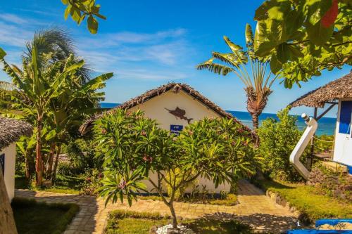 a house with trees and the ocean in the background at Le Grand Bleu in Andilana