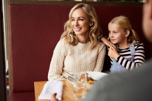 Uma mulher e uma menina sentadas à mesa a comer. em RACV Inverloch Resort em Inverloch