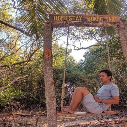 a man sitting on a swing in the woods at Homestay Buang Sari in Gresik