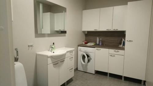 a white kitchen with a sink and a washing machine at Apartment Pistoolintie in Pyhäjoki