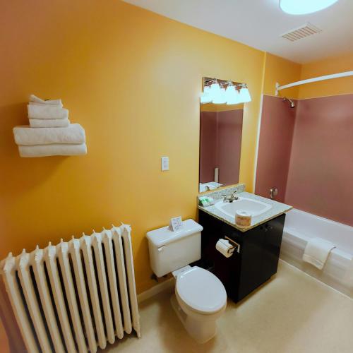 a bathroom with a toilet and a sink and a radiator at James Bay Inn Hotel, Suites & Cottage in Victoria