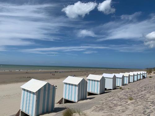 a row of beach huts on a sandy beach at Appartement familial plein centre Hardelot Plage in Hardelot-Plage