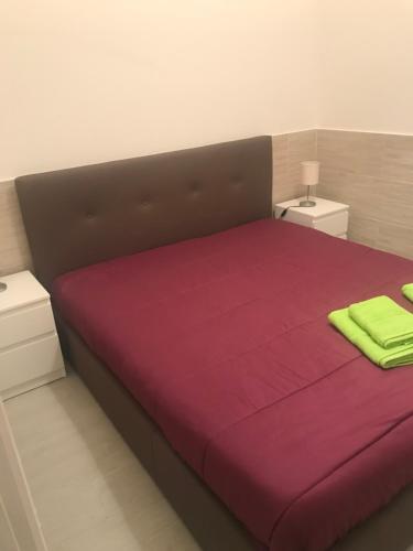 um quarto com uma cama grande com lençóis roxos e verdes em Cartia 91 em Ragusa