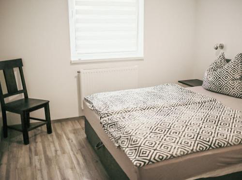 ein Schlafzimmer mit einem Bett, einem Stuhl und einem Fenster in der Unterkunft George Apartman in Sárvár