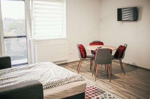Zimmer mit einem Tisch, Stühlen und einem Fenster in der Unterkunft George Apartman in Sárvár