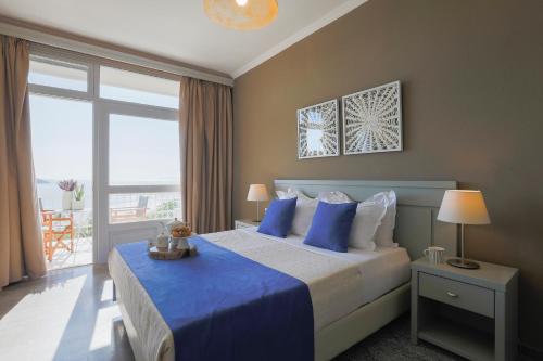 een slaapkamer met een bed met blauwe lakens en een raam bij Irida Aegean View, Philian Hotels and Resorts in Megali Ammos