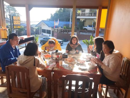 a group of people sitting around a table eating at Hill Top Home in Mae Salong