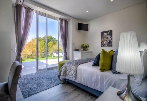 een slaapkamer met een bed en een groot raam bij Badgemore Villa Guesthouse in Kaapstad