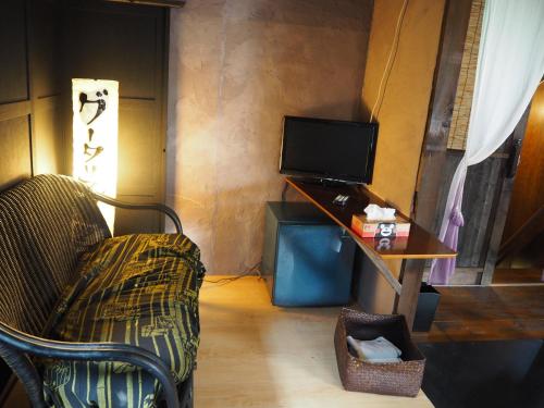 a living room with a chair and a television at 民泊カフェ Gootarian in Kumamoto