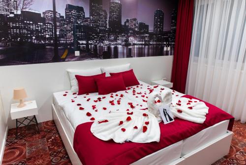 a bedroom with a bed with red pillows and white sheets at Hotel Biss in Zenica