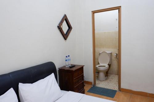 a bedroom with a bed and a toilet and a mirror at Khresna Guest House Malioboro Mitra RedDoorz in Yogyakarta