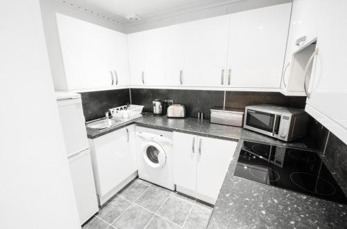 
a kitchen with a microwave, sink, and dishwasher at Argyll Apartments in Glasgow

