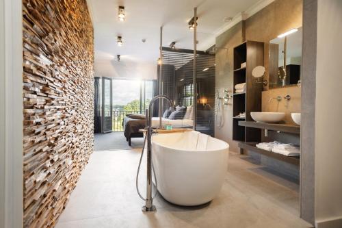 a bathroom with a white tub in a room at Hotel Restaurant De Wolfsberg in Groesbeek