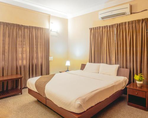 um quarto com uma cama grande e cortinas em Hanu Reddy Residences Wallace Garden em Chennai