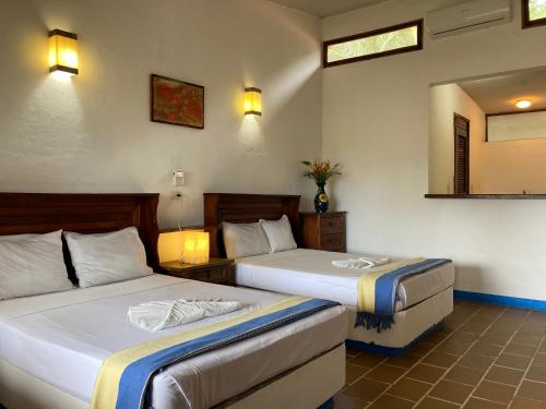 a bedroom with two beds and a mirror at Hotel Arcoiris in Puerto Escondido