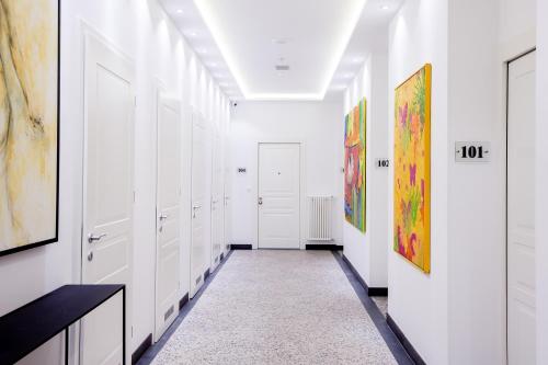 a hallway with white closets and paintings on the walls at White House Bela Hiša in Ljubljana