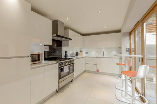 a white kitchen with white appliances and orange chairs at Destiny Scotland - Q-Residence in Edinburgh