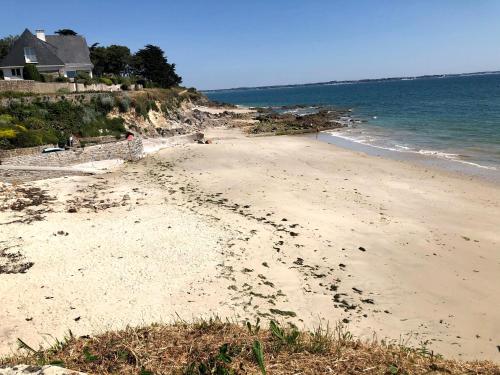 a beach with footprints in the sand and the ocean at O Bord de la mer in Saint-Pierre-Quiberon