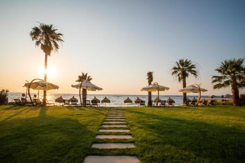 a pathway with umbrellas on the beach with the ocean at MAIA Luxury Beach Hotel & Spa in Guzelcamlı