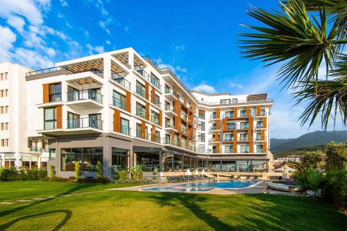 un bâtiment avec une piscine et un palmier dans l'établissement MAIA Luxury Beach Hotel & Spa, à Güzelçamlı
