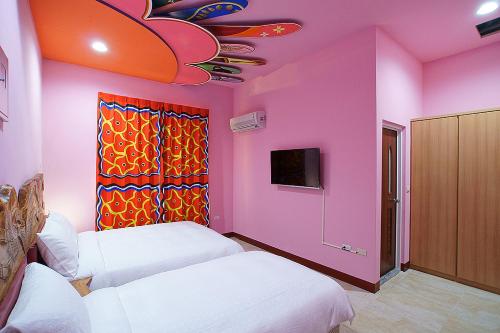 a room with two beds and a pink wall at Makabahi B&B in Taitung City