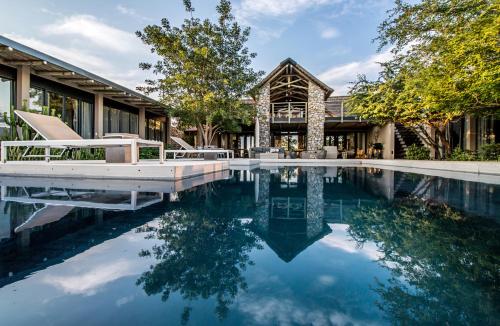 a house with a swimming pool in front of a house at Kruger Sunset Lodge in Hectorspruit