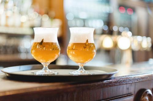 two glasses of beer on a plate on a bar at Hotel Restaurant De Wolfsberg in Groesbeek