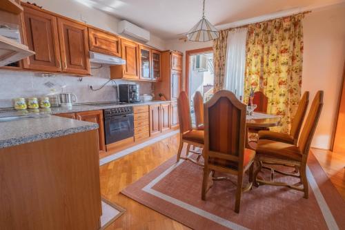 a kitchen with wooden cabinets and a table and chairs at Apartman Anđelko in Jadranovo