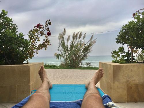 a man laying on a mat with his feet on the beach at Covo dei Marinai in Cava dʼAliga