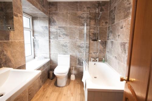 a bathroom with a toilet and a tub and a sink at Duke Of Gordon Hotel in Kingussie