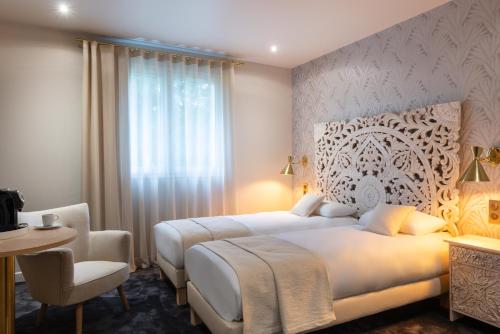 a bedroom with a large white bed and a chair at The Originals Boutique, Parc Hôtel, Orléans Sud in La Chapelle-Saint-Mesmin
