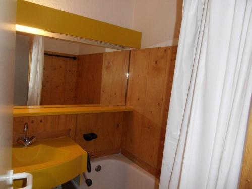 een badkamer met een wastafel, een bad en een douchegordijn bij travelski home classic - Résidence Themis in La Plagne