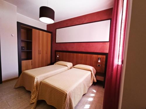two beds in a room with red walls at Hotel Naitendì in Cutrofiano