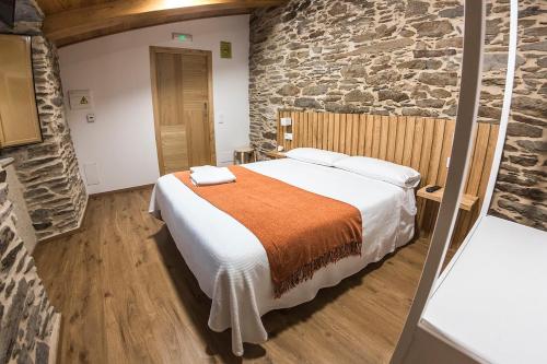 a bedroom with a bed and a stone wall at Hotel O Pozo in O Pino 