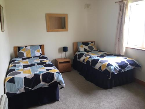a bedroom with two beds and a window at Cliff View, 2 Knockrahaderry in Liscannor