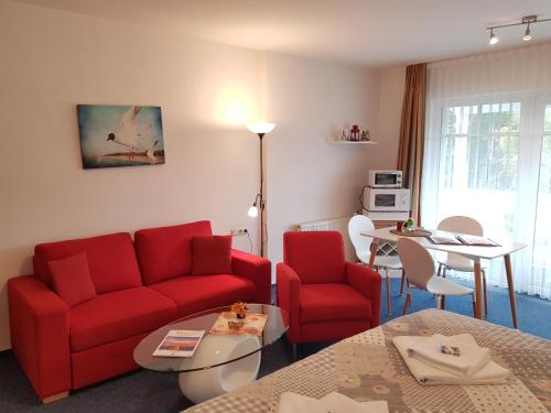 sala de estar con sofá rojo y mesa en Studio 22 Residenz Seeblick, en Ostseebad Sellin