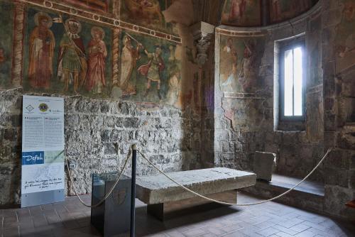 a room with a bench in a church with paintings at Alloggio Turistico Centro Storico Malatesta in Montefiascone