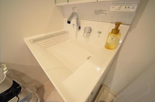 ein Waschbecken im Badezimmer mit einer Flasche Öl darauf in der Unterkunft River Side Namba 200 in Osaka