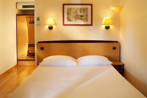 a bedroom with a large white bed with two pillows at Campanile Alençon in Alençon